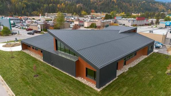 Aerial view of The Confluence building in Castlegar, BC — a modern mass-timber hub with a multi-angled metal roof